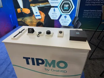 TIPMO hardware on display at the GratifID booth, including smartwatches, NFC tags, and contactless tipping devices